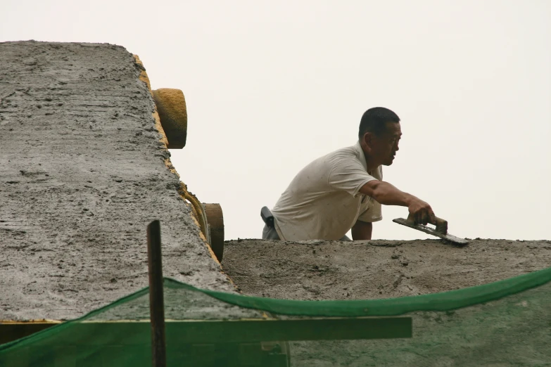 man sitting at top of concrete platform in unfinished area