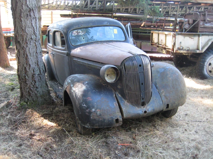 an old pick up truck sits next to a tree