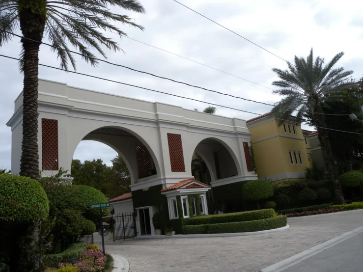 a building with arches, archways and bushes on the sidewalk