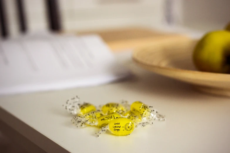 a white table topped with yellow candies next to an apple