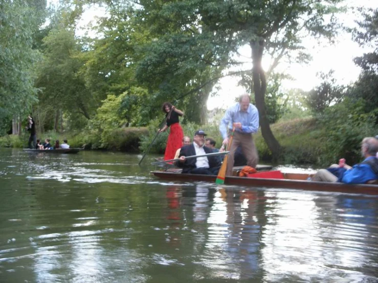 people riding in boats on the water with trees