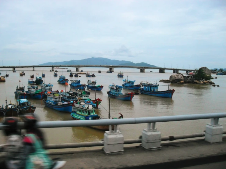 a bridge with many fishing boats floating in it