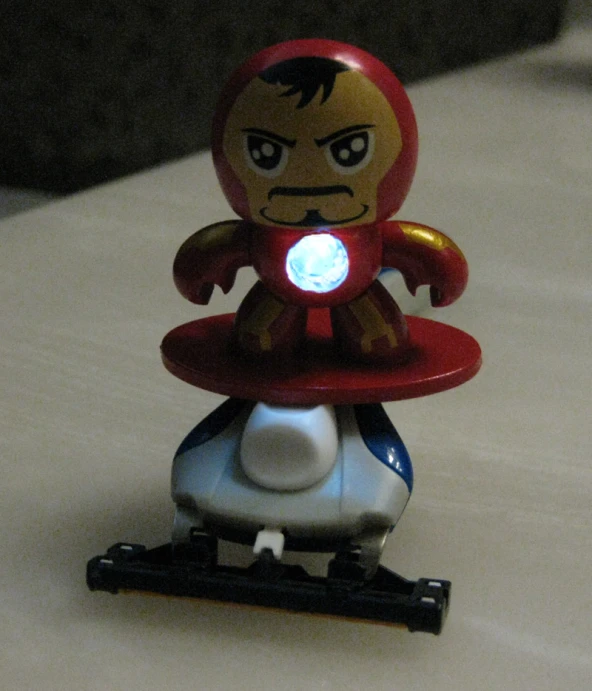 a red toy robot with blue eyes riding a white bicycle