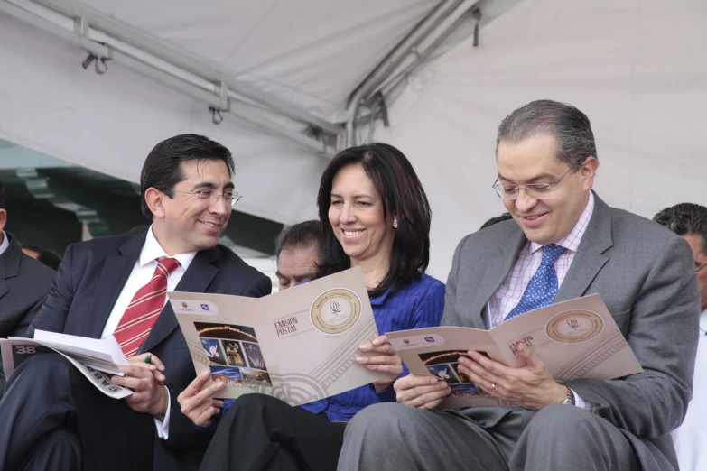 people in suits smiling while holding pamphlets