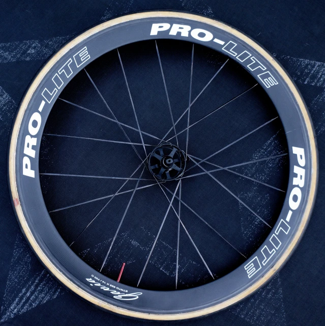 a bicycle wheel with white lettering sitting on top of a dark blue surface
