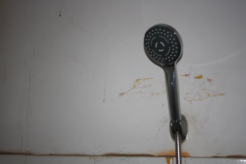 a shower head in an old dirty restroom