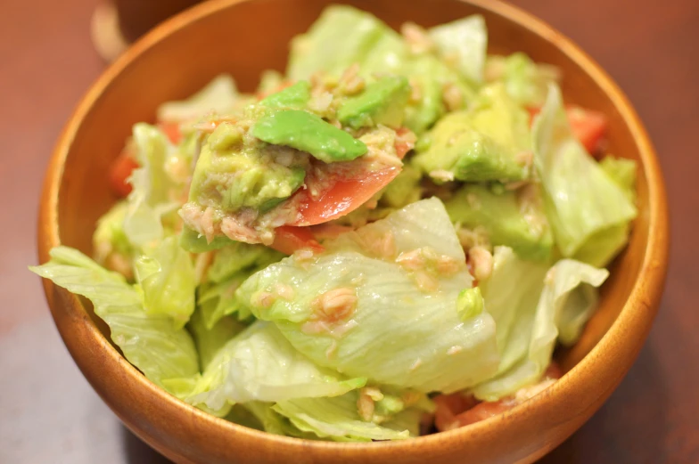 there is a brown bowl with lettuce and tomato salad