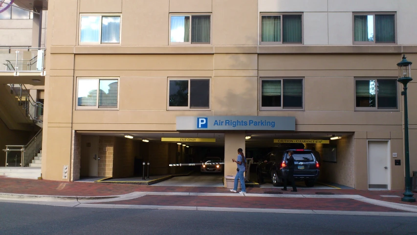 a man stands by his vehicle in front of the parking garage