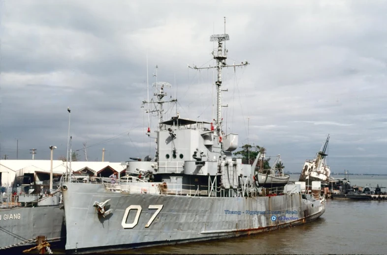 an old grey military ship docked at the pier