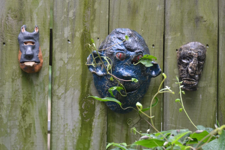 several colorful masks on a wooden fence
