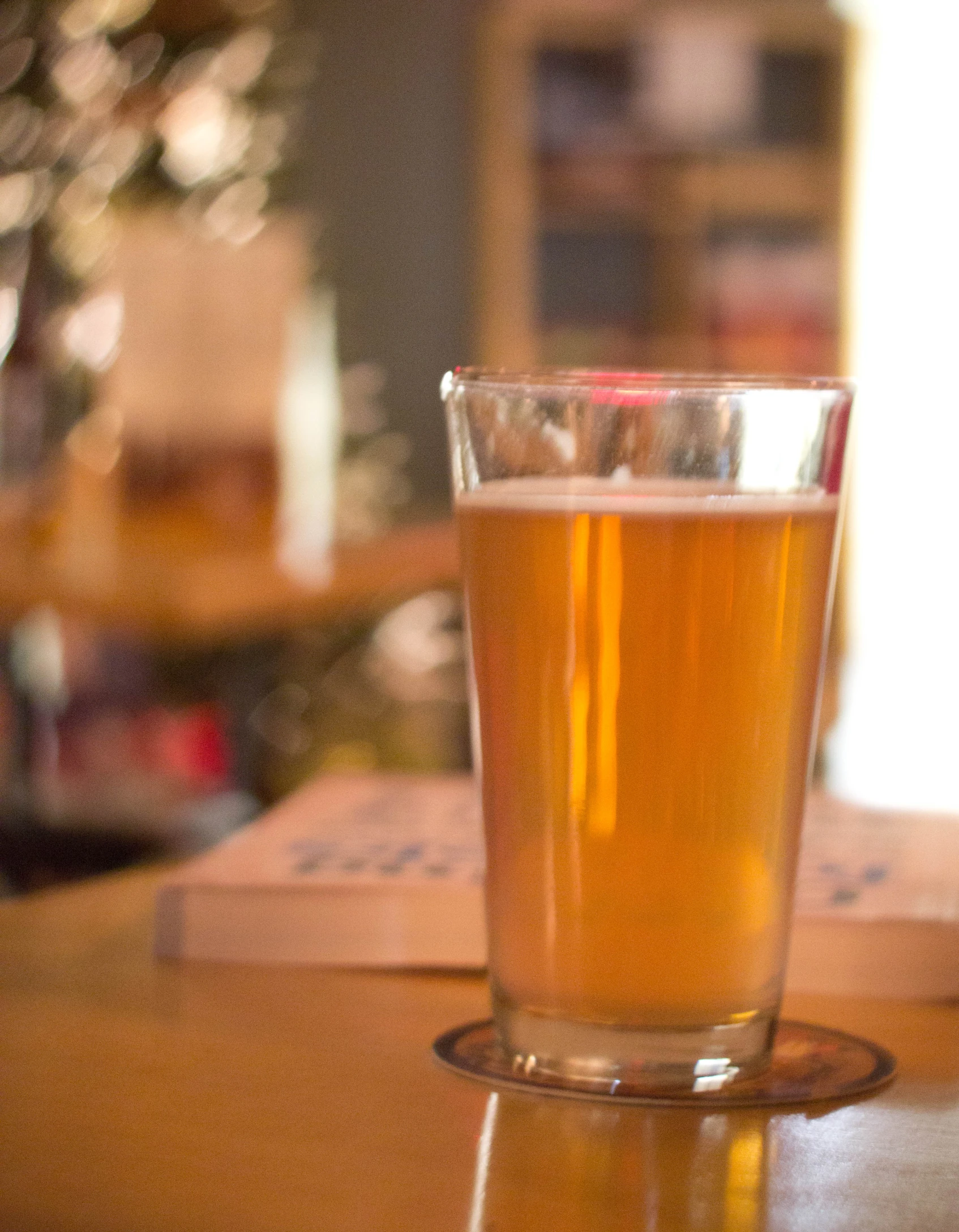 a beer glass sits on a table with two boxes nearby