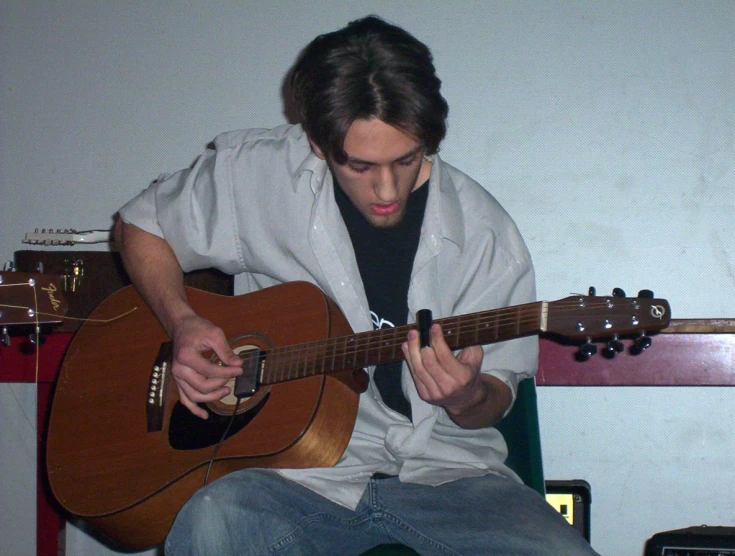 a man sits playing an acoustic guitar