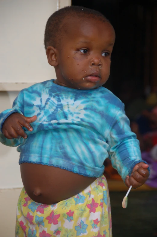 a child in blue is chewing on a toothbrush