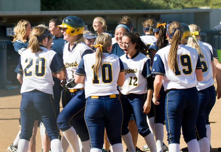 a softball team in a huddle wearing white and blue outfits