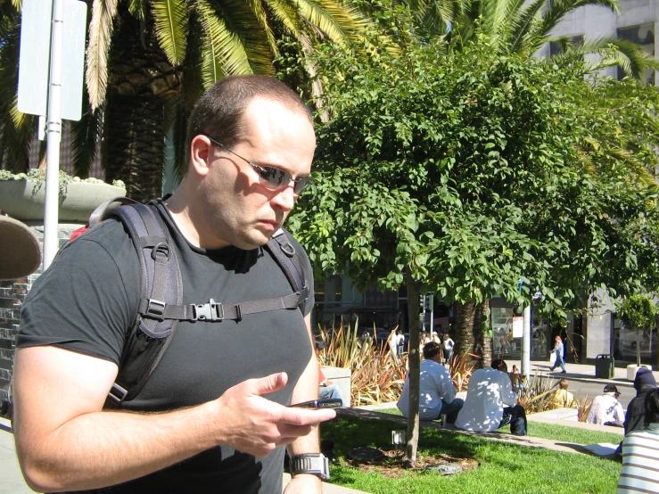 a man standing in the grass checking his cell phone