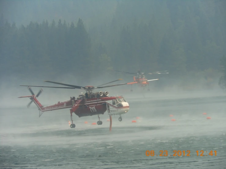 a red helicopter with three smaller helicopters standing in the fog