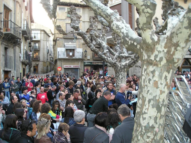 people walking and standing around on a crowded sidewalk