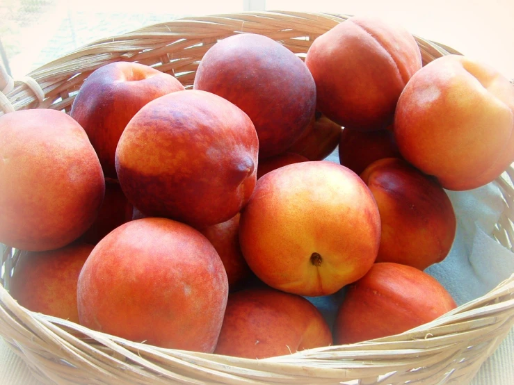 a basket filled with lots of peaches on top of a table