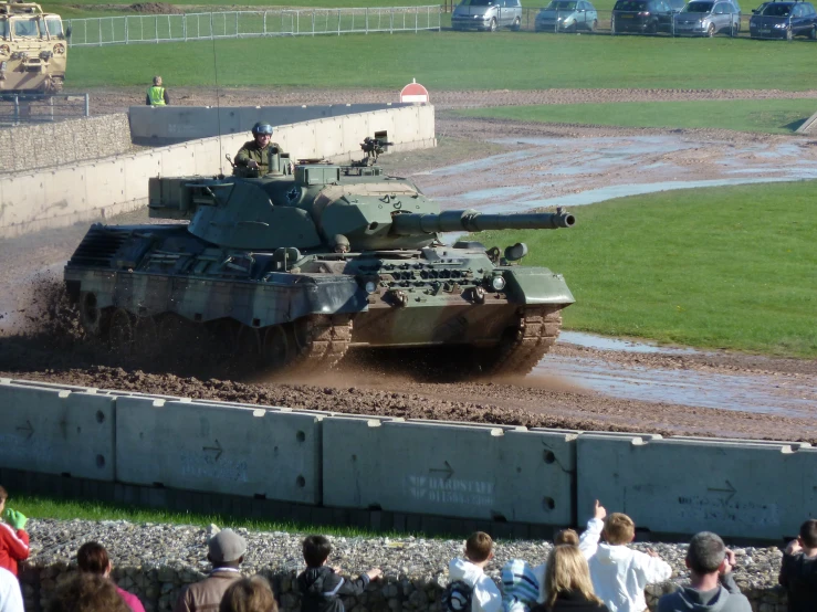 tank is moving through mud in front of people