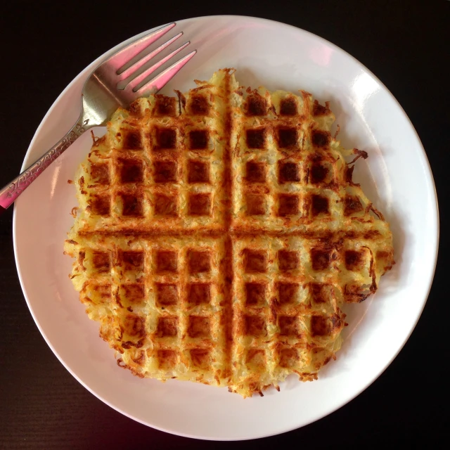 a white plate holding waffles, a fork and a knife