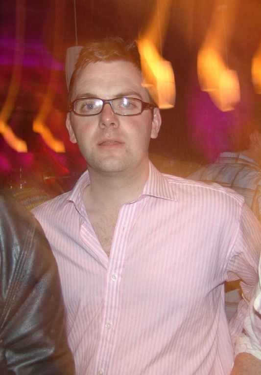 a man with glasses in a pink shirt