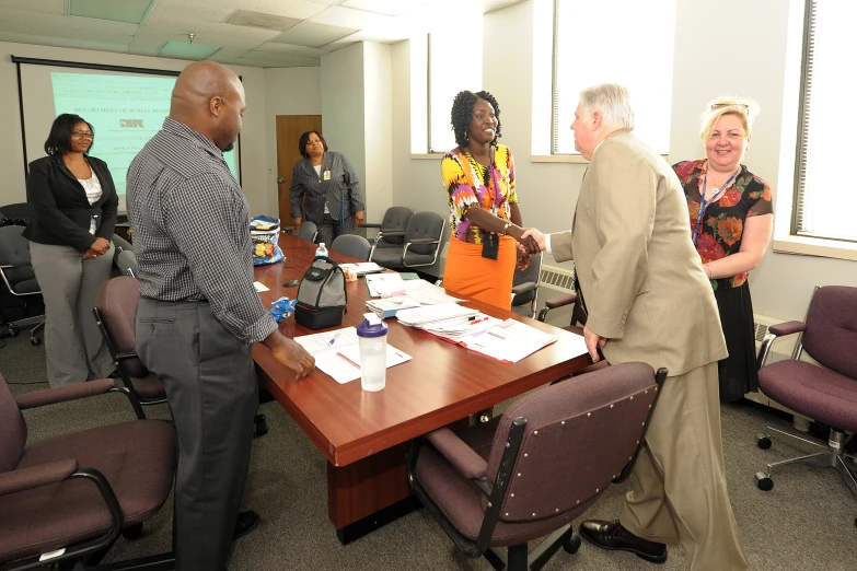 men and women standing around a table in an office