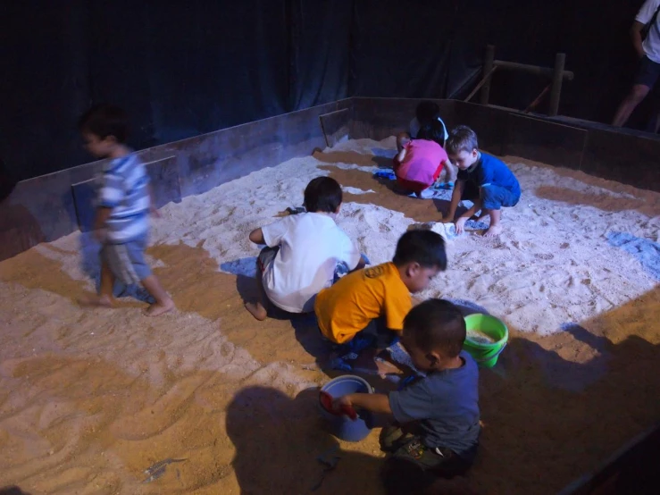 a group of children playing in sand with toys