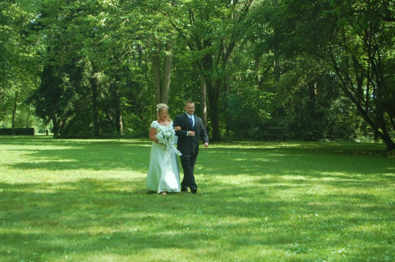 the bride and groom are standing in the field near the trees