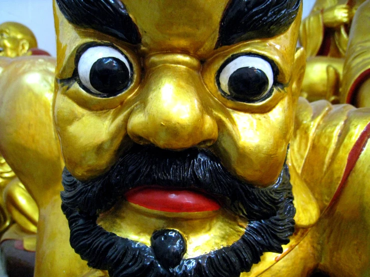a golden statue with a fake beard has two large eyes