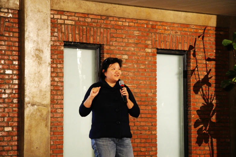 a person standing in front of a red brick wall holding a microphone