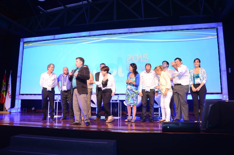 a group of people standing on a stage holding up signs