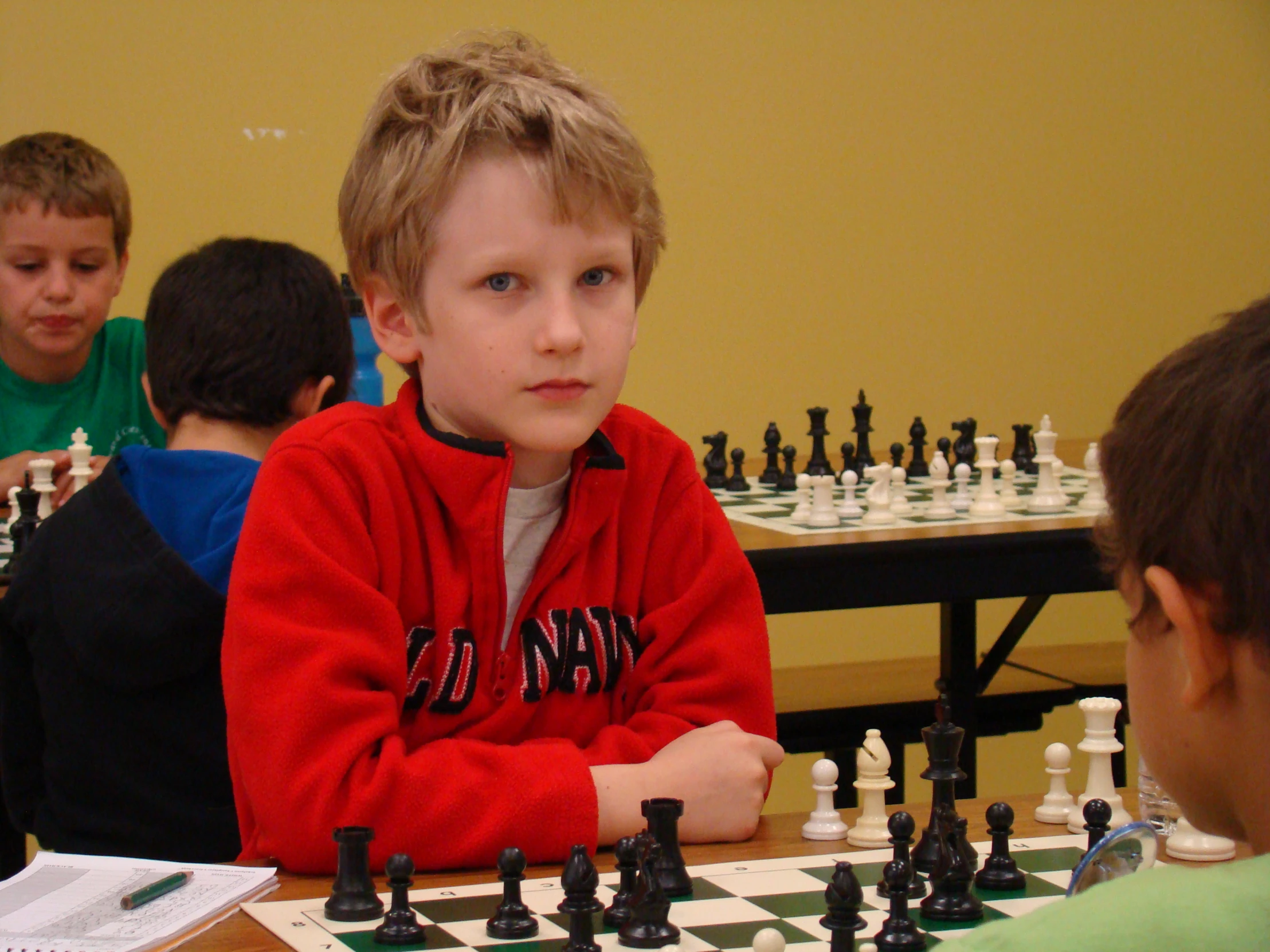 two boys playing chess at the table with others