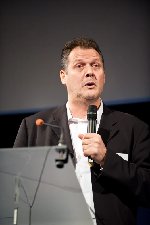 a man holds a microphone and speaks into a mic
