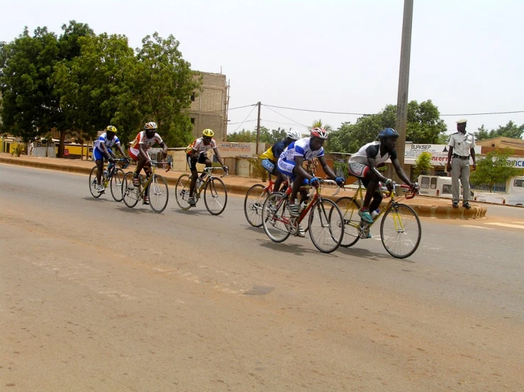 a group of bikers race down a street lined with telephone poles