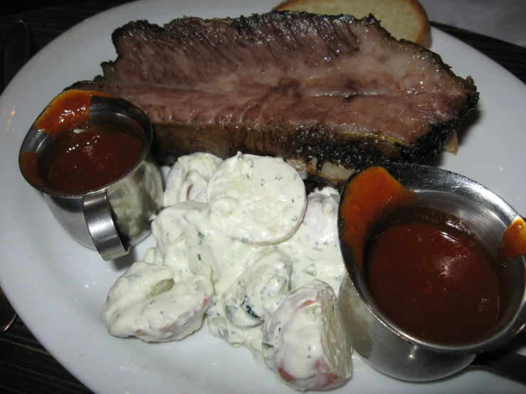 a plate with meat, sour cream and sauce on it