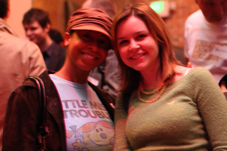 two women with hats smiling in the middle of a group of people