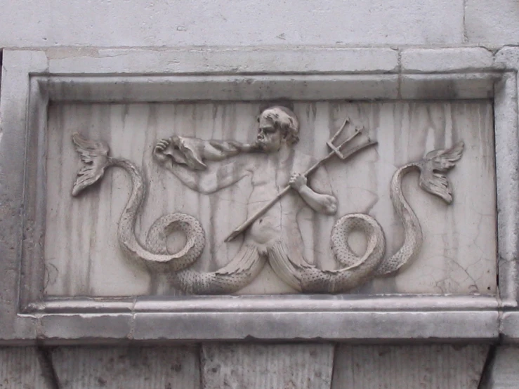 a sculpture on a building featuring an angry devil holding two snakes