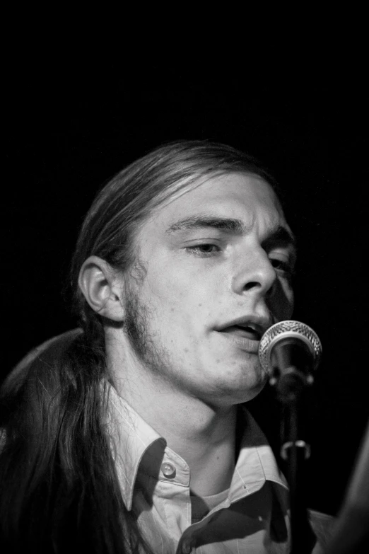 a man with long hair and an earring near a microphone