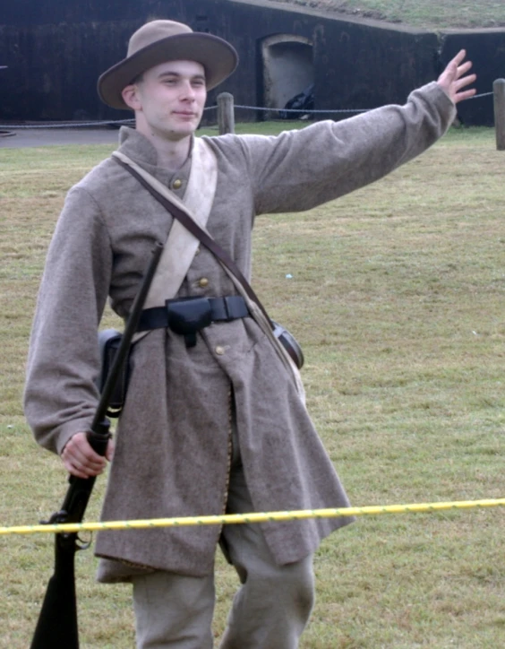 a man in an old uniform holds his rifle while standing outside