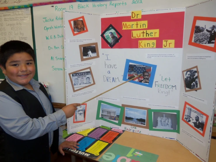 a boy with his project displayed in the classroom