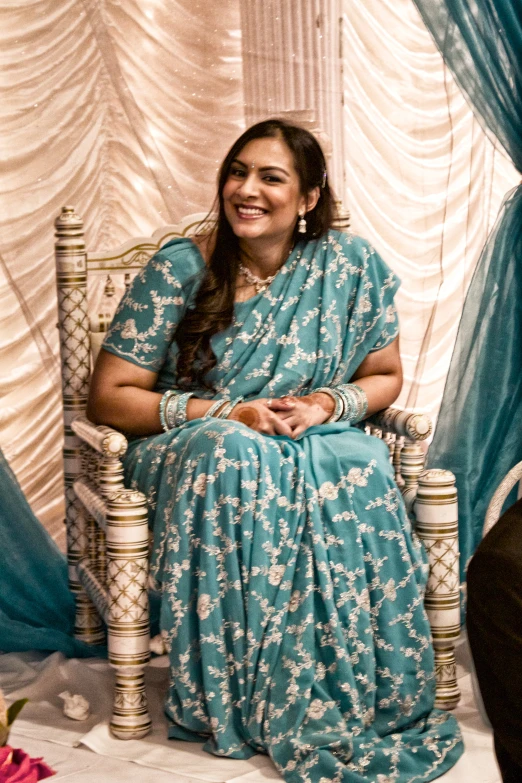 woman in traditional indian blue sari sitting on a chair