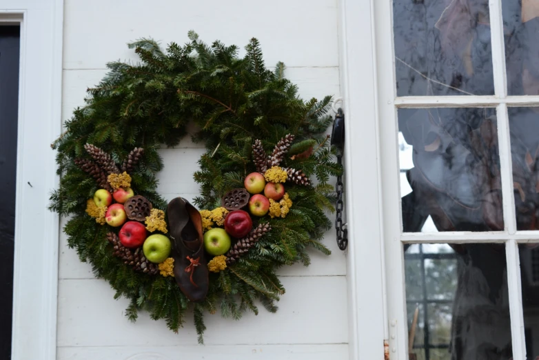 a wreath with fruit and pine cones hangs on a building's wall