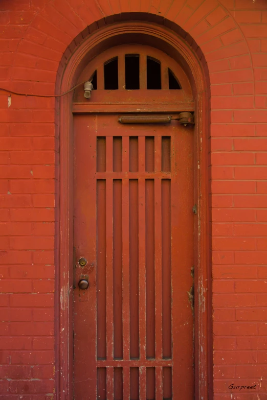 an orange gate is on the side of a red wall