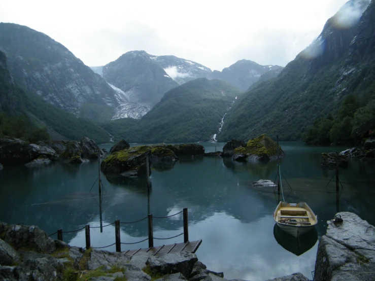 a boat is sitting on the water in front of mountains