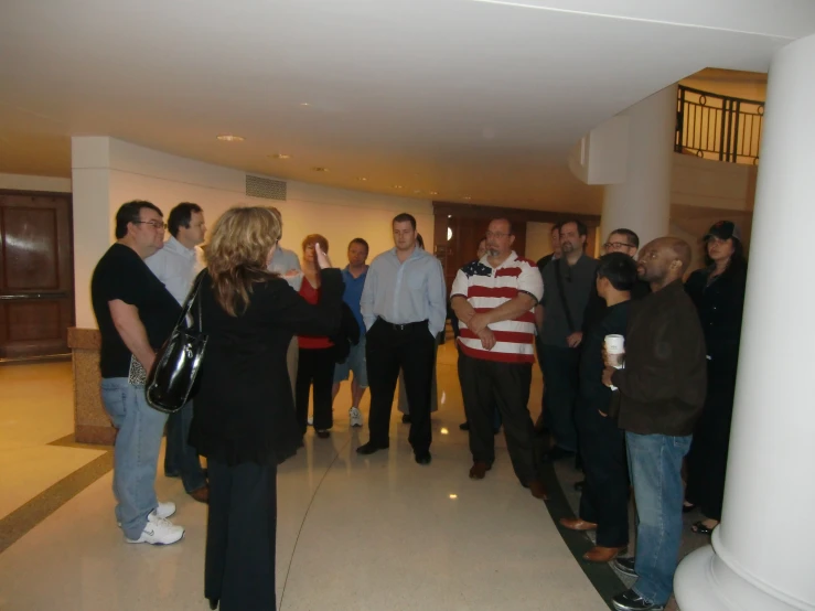 people gather in a room together with a white column