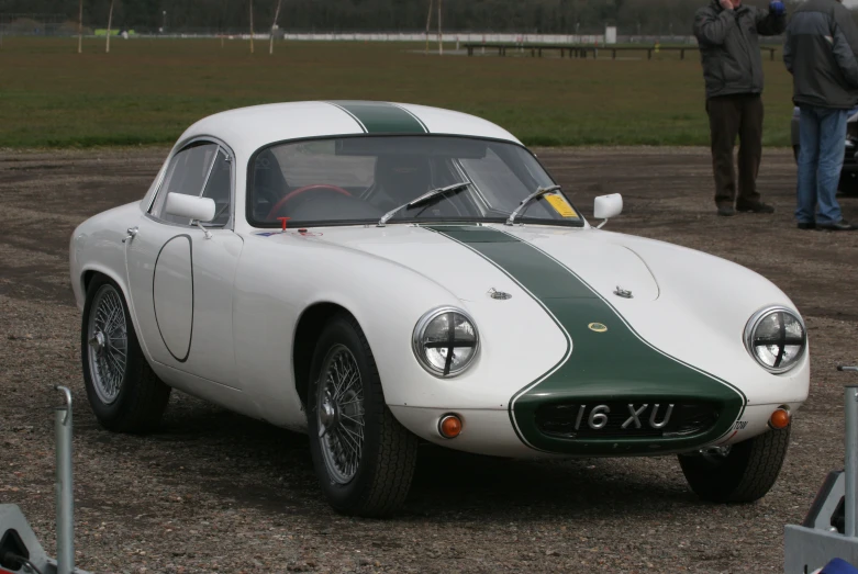 a sports car is in the gravel as people look on