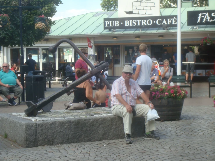 a man sitting on a stone bench next to a large old fashioned pirate ship