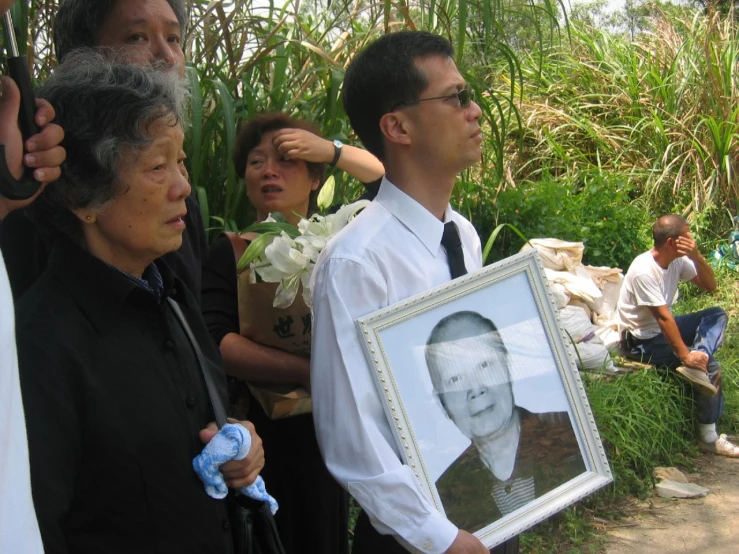 an elderly man holding a picture of his baby and people watching