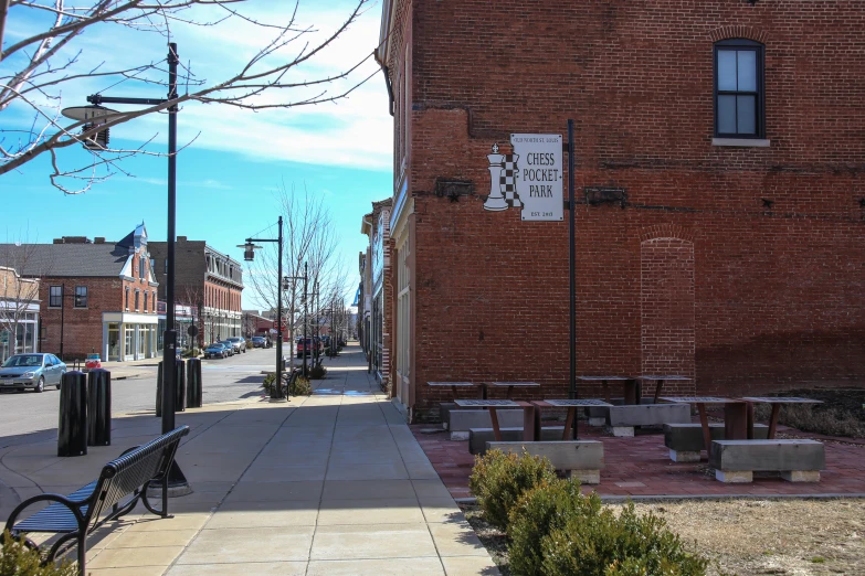 an empty sidewalk with benches on the side