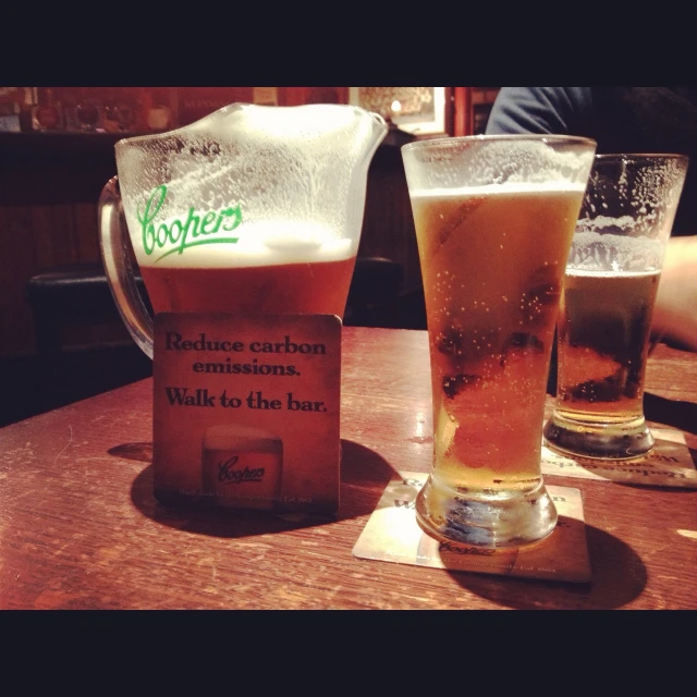 two glasses of beer sit on a table in a bar